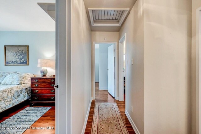 corridor with baseboards, visible vents, and wood finished floors