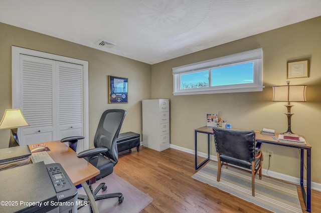 office area featuring baseboards, visible vents, and wood finished floors