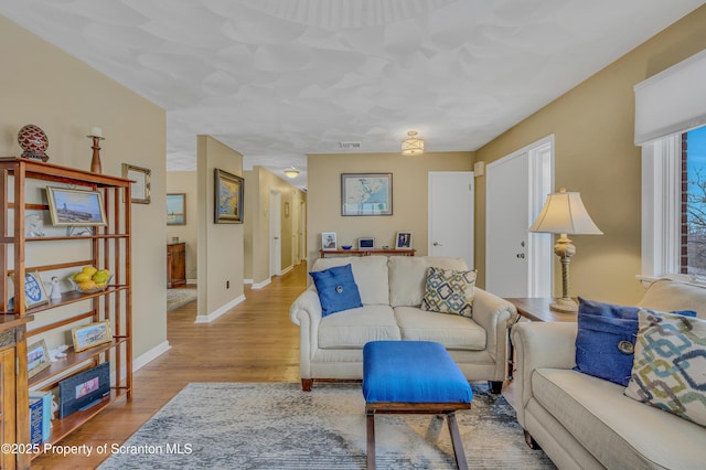 living area featuring baseboards, visible vents, and wood finished floors