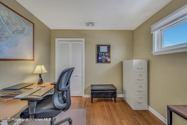 office area with light wood-style floors, baseboards, and visible vents