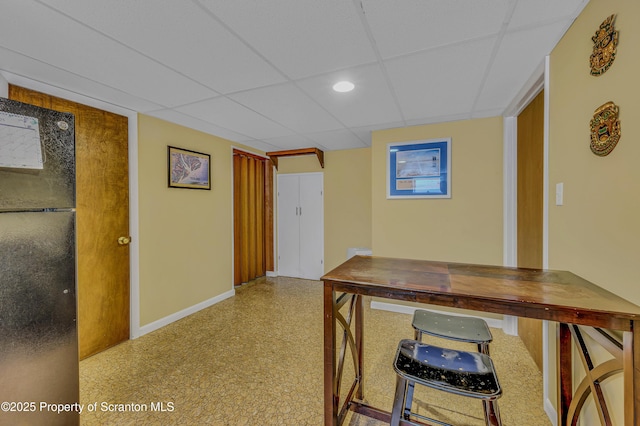 home office with a drop ceiling and baseboards