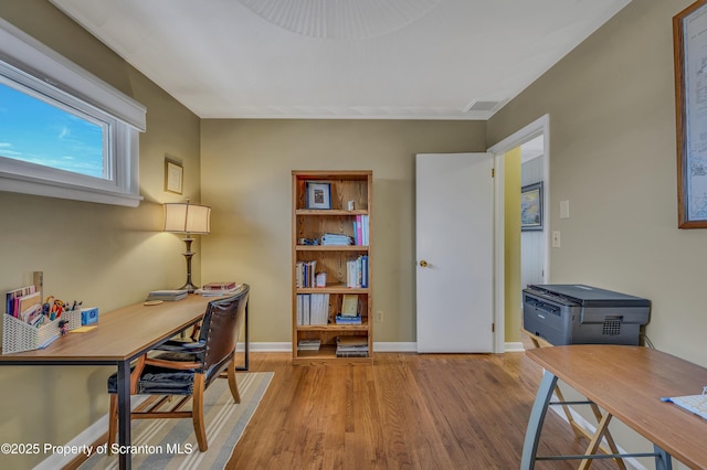 office space with light wood finished floors, visible vents, and baseboards