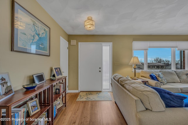 living area featuring baseboards and light wood finished floors