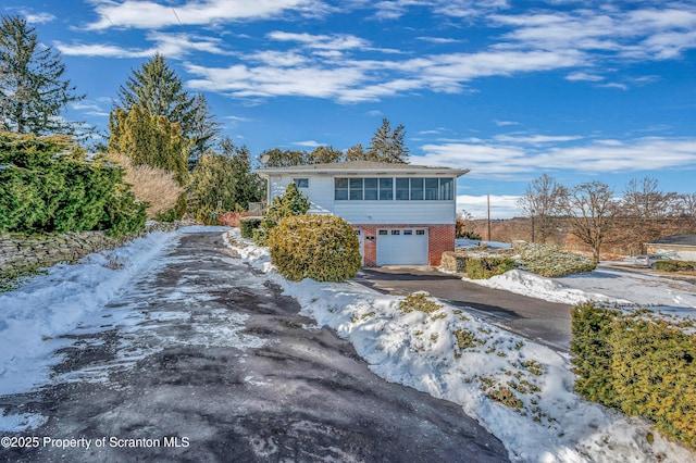 exterior space with brick siding, an attached garage, and aphalt driveway