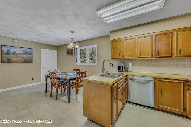 kitchen with a peninsula, a sink, light countertops, dishwasher, and pendant lighting