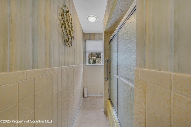 hall with light tile patterned floors and tile walls