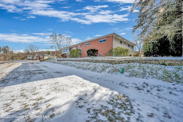 snow covered property featuring brick siding