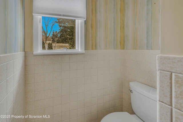 bathroom featuring toilet and tile walls