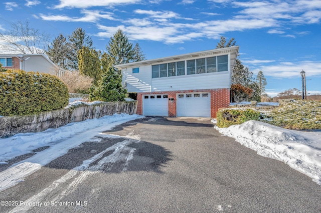 view of front of home featuring a garage, aphalt driveway, and brick siding