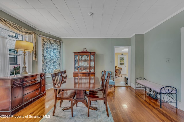 dining space with ornamental molding and light wood-type flooring