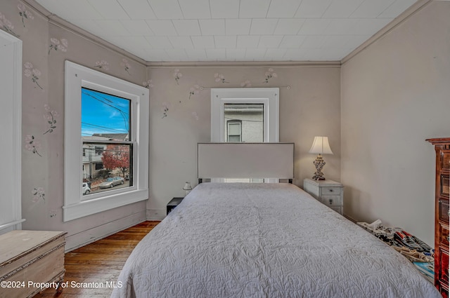 bedroom with hardwood / wood-style flooring and ornamental molding