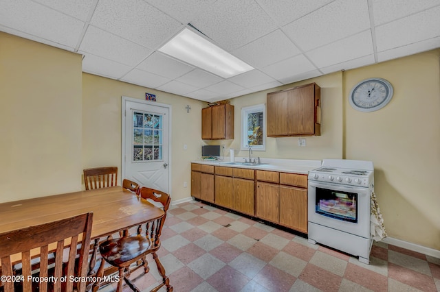 kitchen featuring white stove, a paneled ceiling, and sink