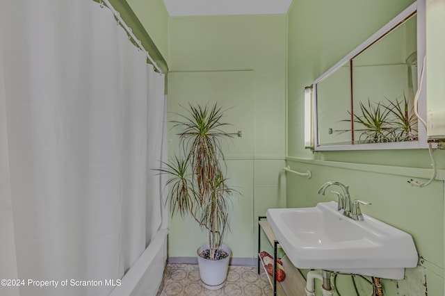 bathroom featuring shower / tub combo with curtain and sink