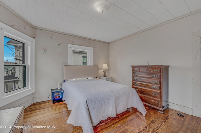 bedroom with multiple windows, light hardwood / wood-style flooring, and ornamental molding