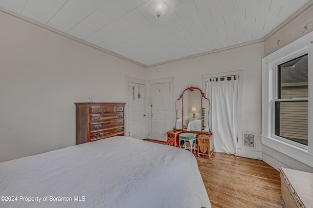 bedroom featuring light wood-type flooring and crown molding