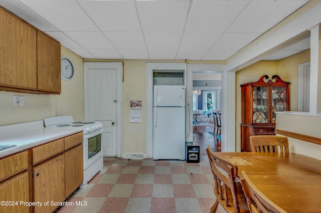 kitchen featuring white appliances and a drop ceiling