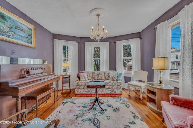 living area with a chandelier, a textured ceiling, and light wood-type flooring