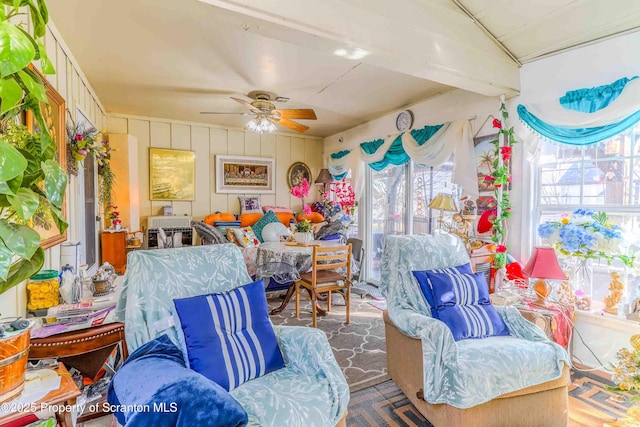 living area featuring beamed ceiling and ceiling fan