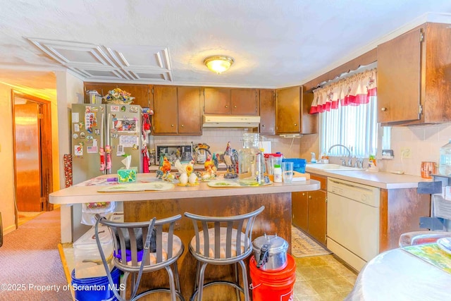 kitchen with sink, stainless steel fridge, white dishwasher, a kitchen island, and decorative backsplash