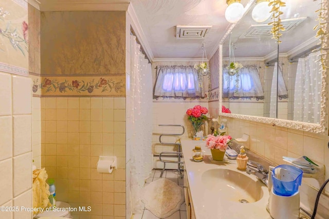 bathroom featuring ornamental molding, sink, and tile walls