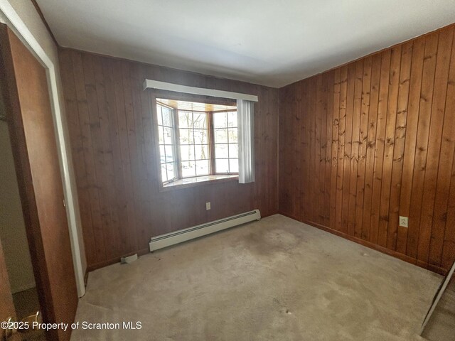 203 Willow Rd, Dalton, PA 18414 - empty room with a baseboard heating unit, wooden walls, and carpet flooring