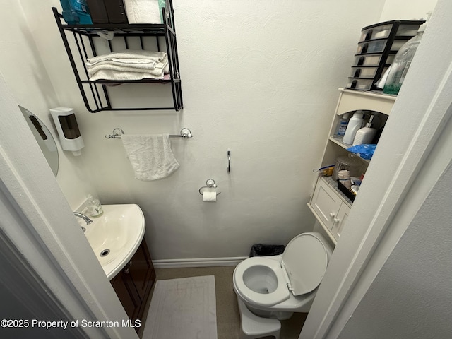 half bathroom with toilet, vanity, and baseboards