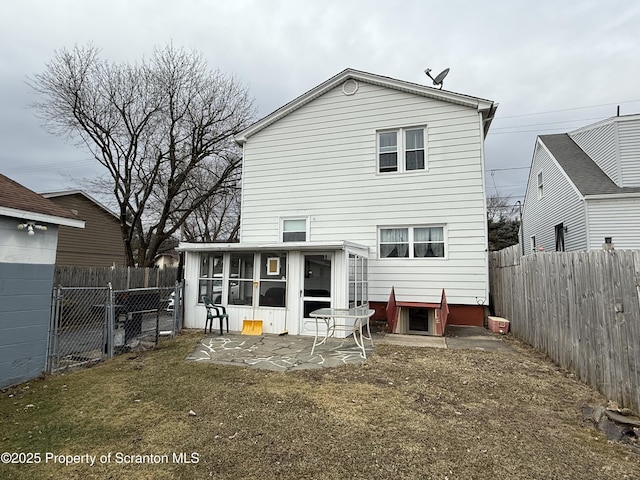 back of house with a patio area, a sunroom, a fenced backyard, and a gate