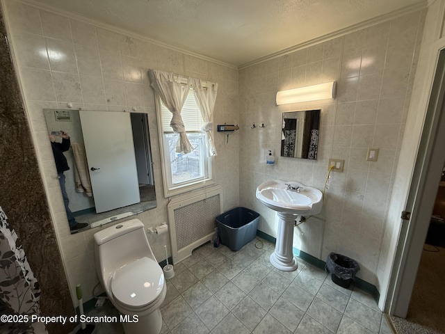 half bath featuring tile walls, radiator, toilet, ornamental molding, and tile patterned floors