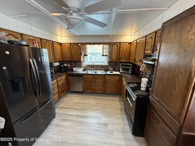 kitchen with appliances with stainless steel finishes, decorative backsplash, a sink, and brown cabinets