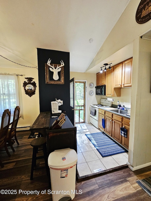 55 Lyman Ln, Gouldsboro, PA 18424 - kitchen with white range with electric stovetop, black microwave, vaulted ceiling, baseboard heating, and light wood-style flooring