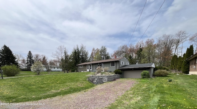 view of front of home featuring a garage, a front lawn, a chimney, and driveway