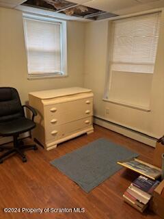 office area with dark hardwood / wood-style floors and a baseboard heating unit