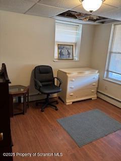 office space featuring a drop ceiling, a baseboard radiator, and hardwood / wood-style flooring