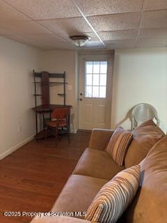 living room featuring a drop ceiling, wood finished floors, and baseboards