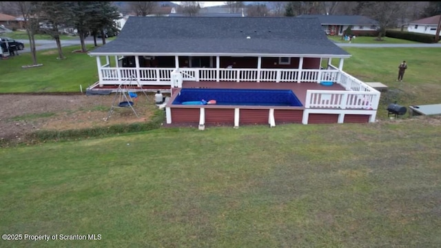 back of property with a pool side deck and a lawn