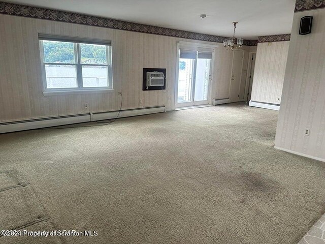 unfurnished room featuring a chandelier, carpet floors, a wall unit AC, and a baseboard radiator