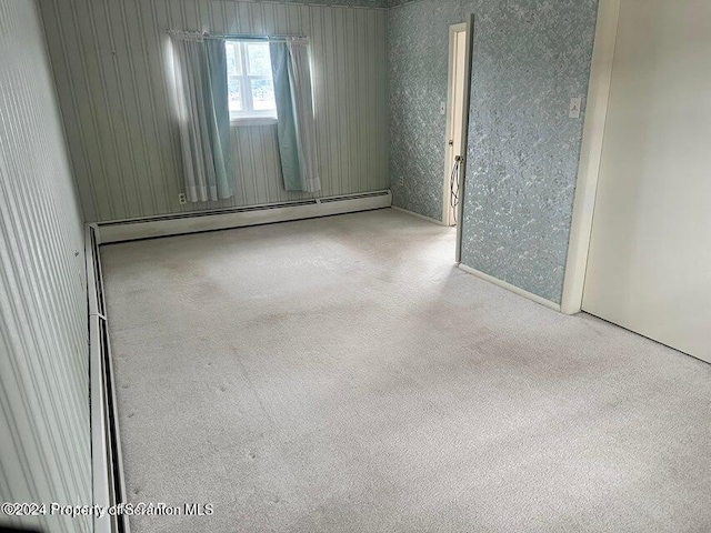 carpeted spare room featuring a baseboard heating unit