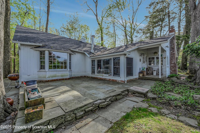 back of house featuring a patio, roof with shingles, and a chimney