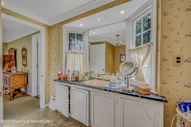 bathroom featuring wallpapered walls, a chandelier, vanity, crown molding, and baseboards