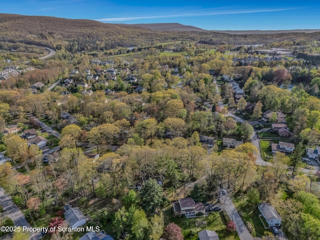 aerial view of property's location with a forest and a mountainous background