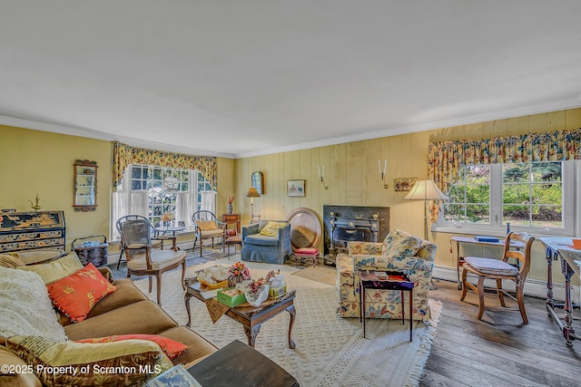 living room featuring ornamental molding, hardwood / wood-style flooring, a wood stove, and wood walls
