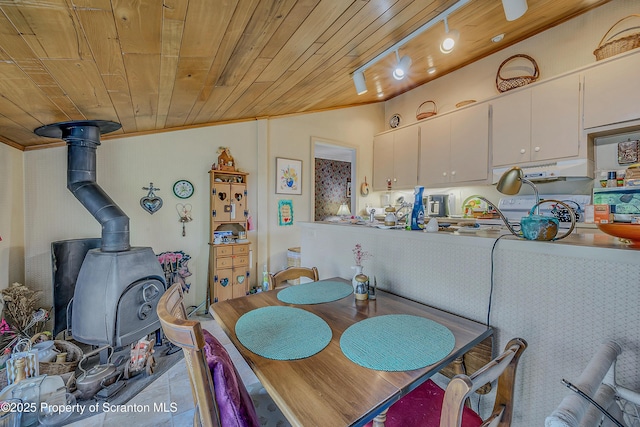 dining room with a wood stove, vaulted ceiling, wood ceiling, ornamental molding, and rail lighting