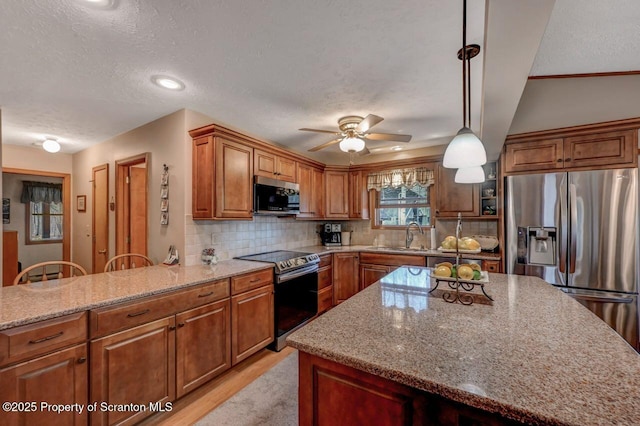 37 S Lehigh River Dr, Clifton Twp, PA 18424 - kitchen featuring stainless steel appliances, brown cabinets, ceiling fan, light stone countertops, and a textured ceiling