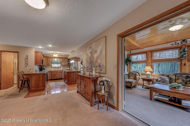 37 S Lehigh River Dr, Clifton Twp, PA 18424 - kitchen featuring light carpet, brown cabinets, a kitchen bar, a sink, and a peninsula