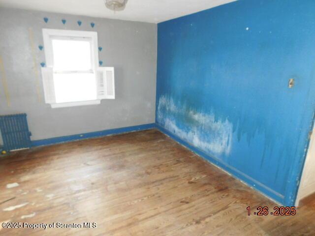 empty room featuring hardwood / wood-style flooring and radiator heating unit