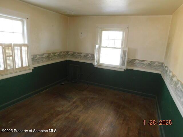 spare room with radiator heating unit and dark hardwood / wood-style flooring