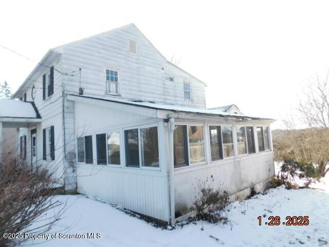 snow covered property with a sunroom