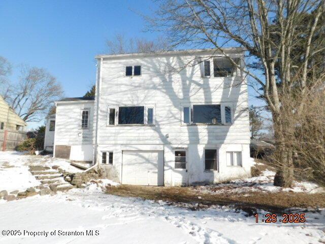 snow covered rear of property with a garage