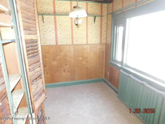 unfurnished room featuring radiator heating unit and wood walls