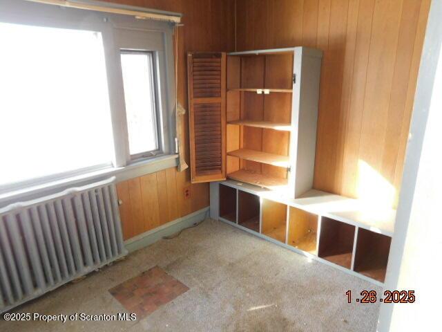 interior space featuring radiator and wood walls